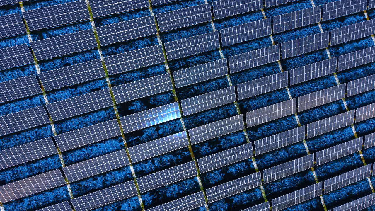 Texture astratta di pannelli solari con tonalità blu. Vista aerea ravvicinata di moduli di pannelli solari blu che creano un motivo a griglia geometrico con riflessi solari.