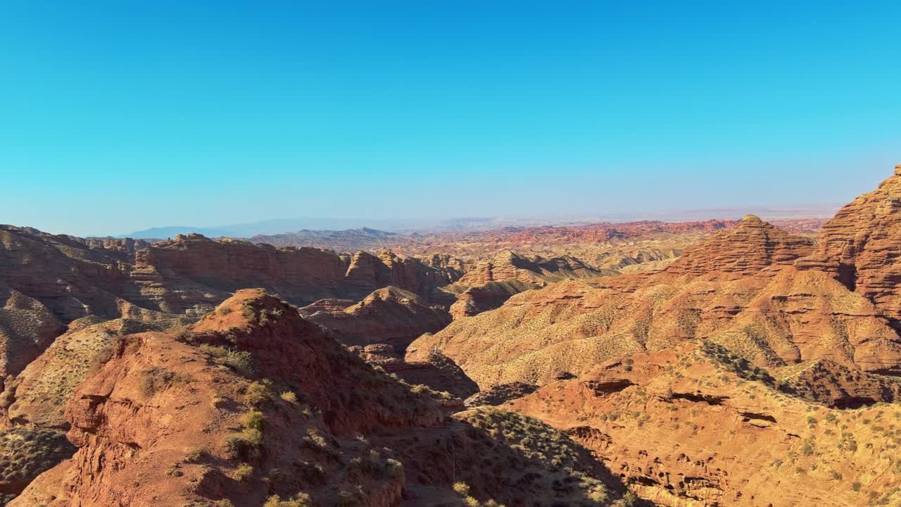 Pingshan Lake Grand Canyon, Zhangye, provincia di Gansu, Cina - Stratificazioni di creste rosse e ocra si estendono attraverso un vasto canyon, scolpite in pieghe scenografiche sotto un cielo azzurro terso - Panoramica a destra