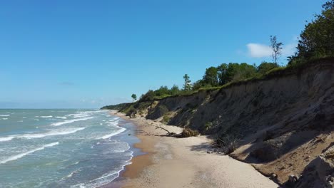 Flying-Over-Coastline-Baltic-Sea-Ulmale-Seashore-Bluffs-Near-Pavilosta,-Latvia-and-Landslides-With-an-Overgrown,-Rippling-Cave-dotted-Cliff-and-Pebbles