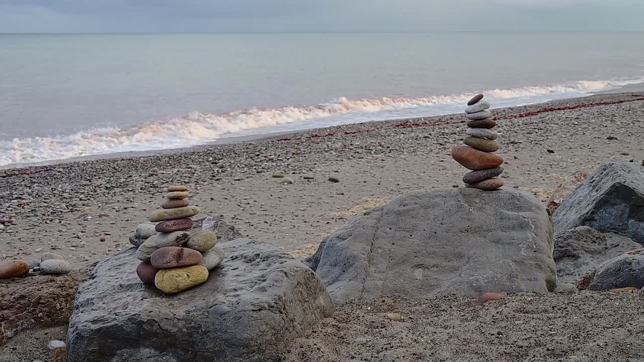 Close-up image of stone mounds by the calmy waving ocean, on a cloudy Fall afternoon in Spain