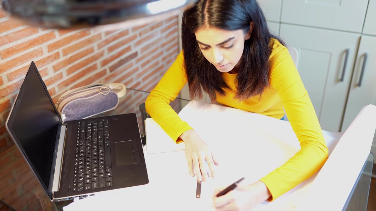 Arquitecta que trabaja en casa con una computadora portátil y planos