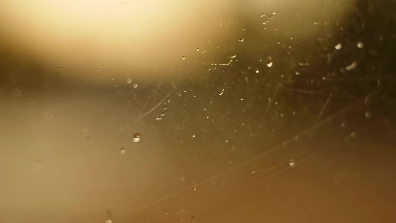 Abstract atmospheric scene with bright golden light glowing from the upper left, soft blurred haze across the frame, and tiny dust particles floating in the air