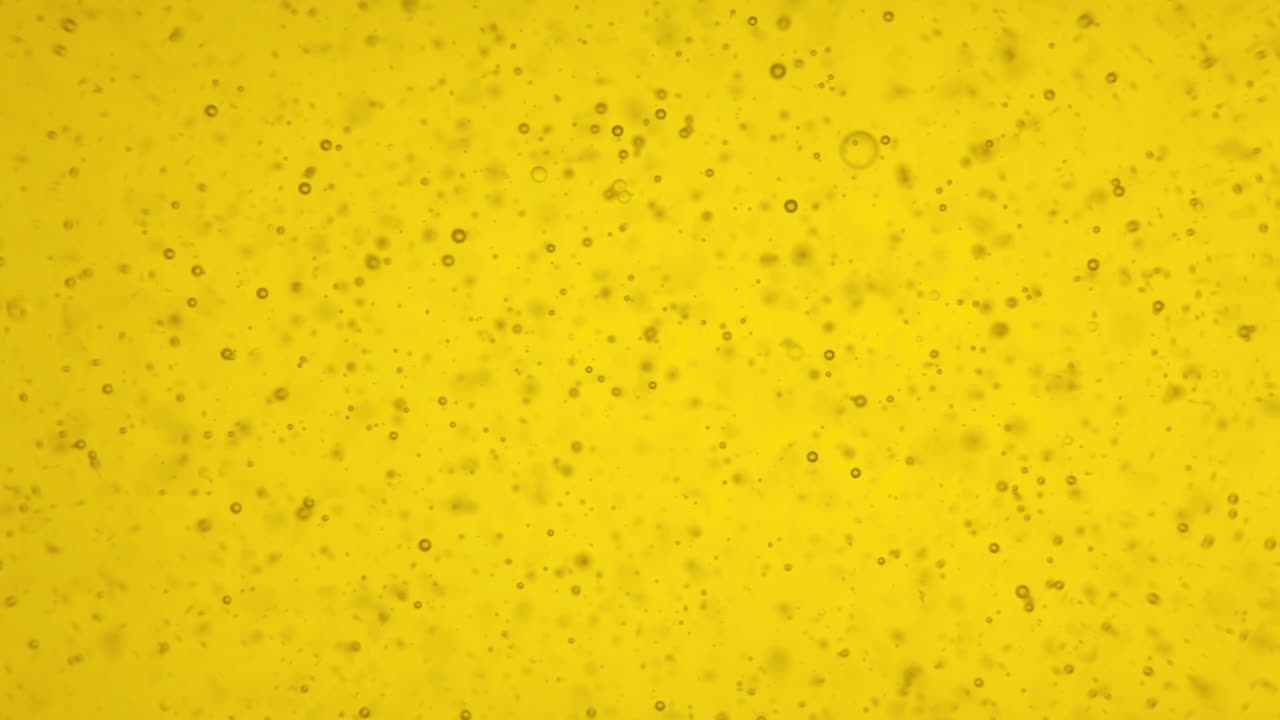 lindas burbujas de aire bailando dentro de un recipiente transparente de aceite de oliva amarillo