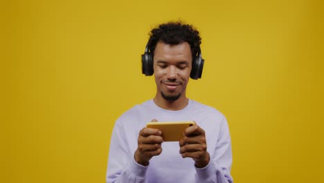 hombre jugando a un juego móvil con auriculares