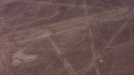aerial video of the famous nazca lines. drone flies above many long linear geoglyphs and a depiction of a spider. located in desert plateau of nazca, peru