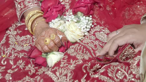 close-up of bride and groom's hands with flowers and traditional attire at a wedding ceremony