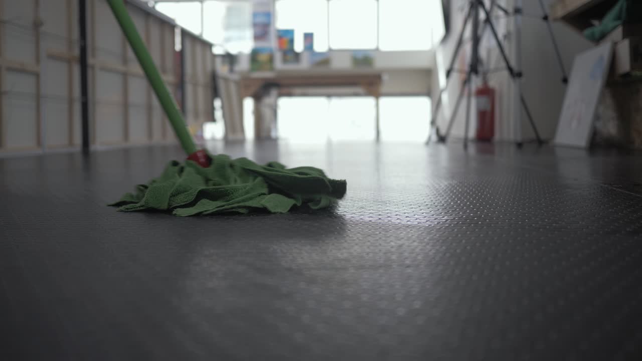 hombre limpiando piso de linóleo usando un trapeador plano medio
