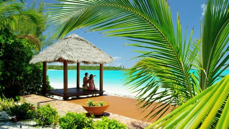 couple sitting in thatched tiki hut on beach