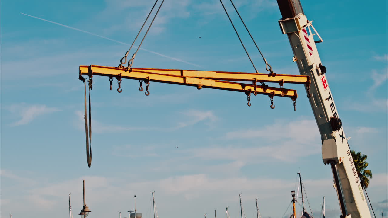 A crane machine moving around with the blue sky and palm trees on the background