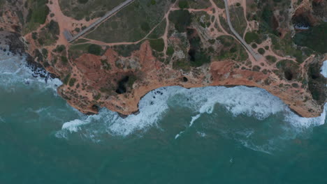 Ojo-De-Pájaro-Aéreo-Arriba-Hacia-Abajo-De-La-Costa-Del-Acantilado-De-Lagos-En-Un-Día-Ventoso,-Portugal,-Drone-Volando-Hacia-Arriba