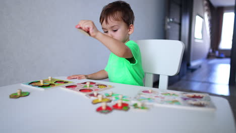 focused baby boy playing with puzzles at desk. cute kid learning fruit through a game.