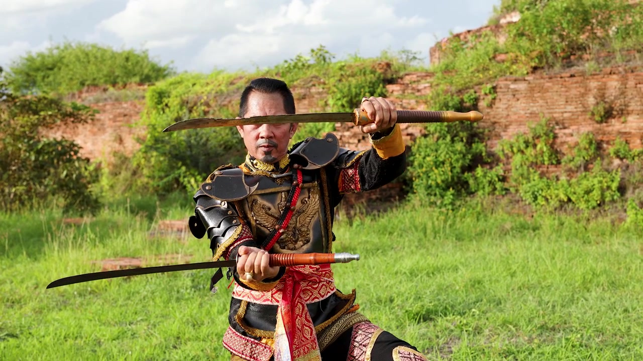 Guerriero thailandese in armatura tradizionale che pratica il combattimento con la spada