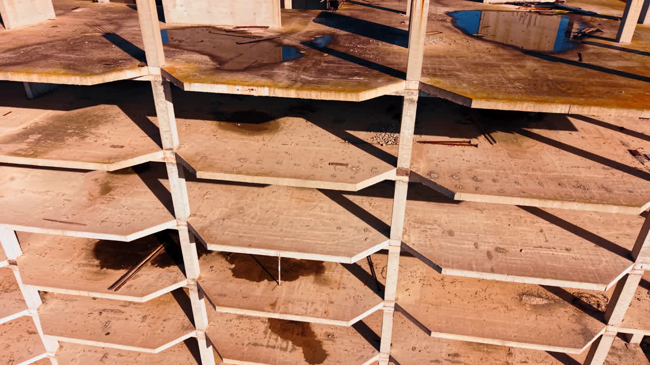 Grandi pozzanghere e alcune barre d'armatura metalliche possono essere viste sui pavimenti dell'edificio incompiuto. Riprese drone attorno al cantiere abbandonato.