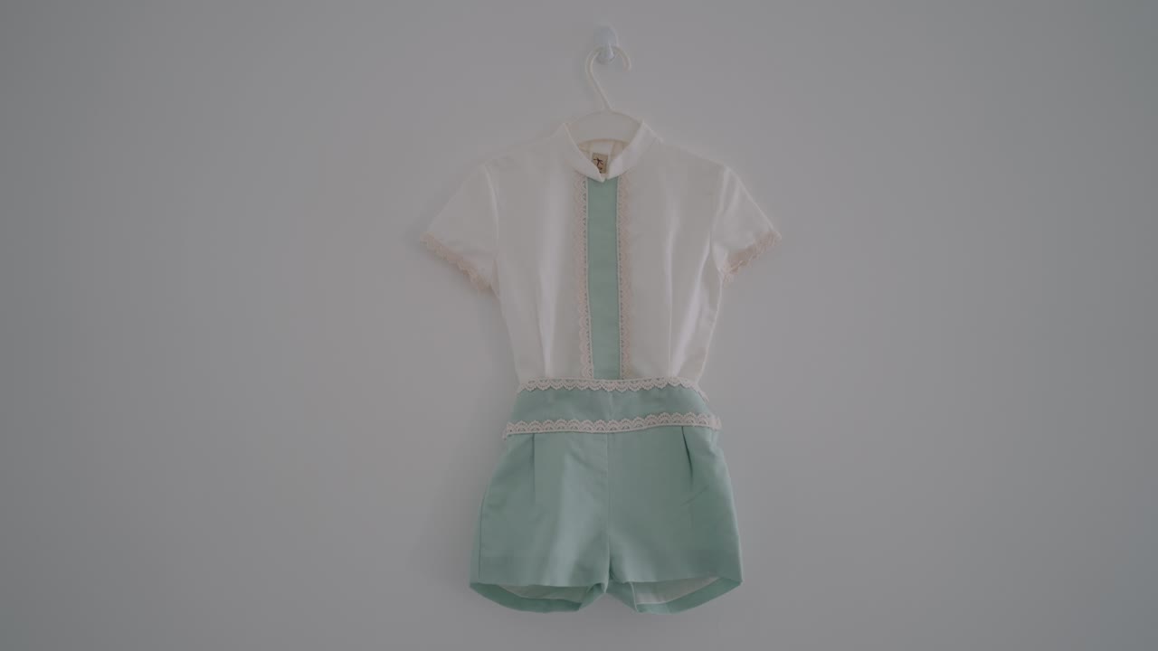 baby romper in mint green and white hanging on wall ready for wedding ceremony