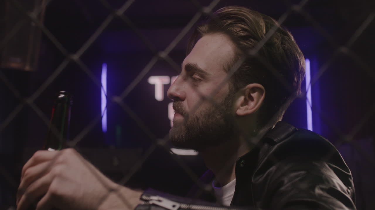 apuesto hombre barbudo bebiendo cerveza y hablando con alguien en la discoteca