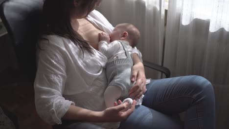 Mother-breastfeeding-newborn-baby-in-armchair-at-home