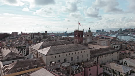 aerial riser from piazza de ferrari reveals grimaldina tower with red cross flag