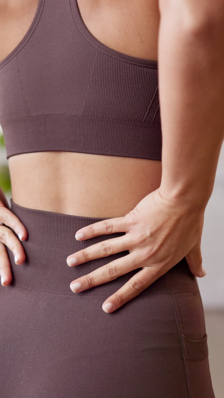 Woman experiencing back pain while wearing workout clothes