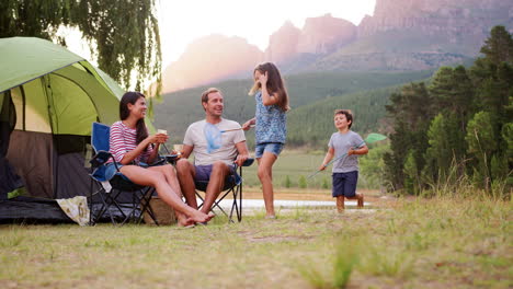 kids run to join parents sitting by tent in rural setting