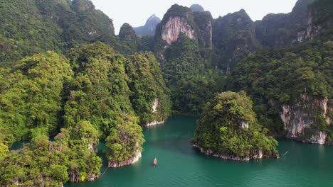 4k drone video flying towards a boat sailing around khao sok national park in thailand