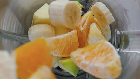 closeup adding fruits blender top view. natural ingredients for vitamin cocktail