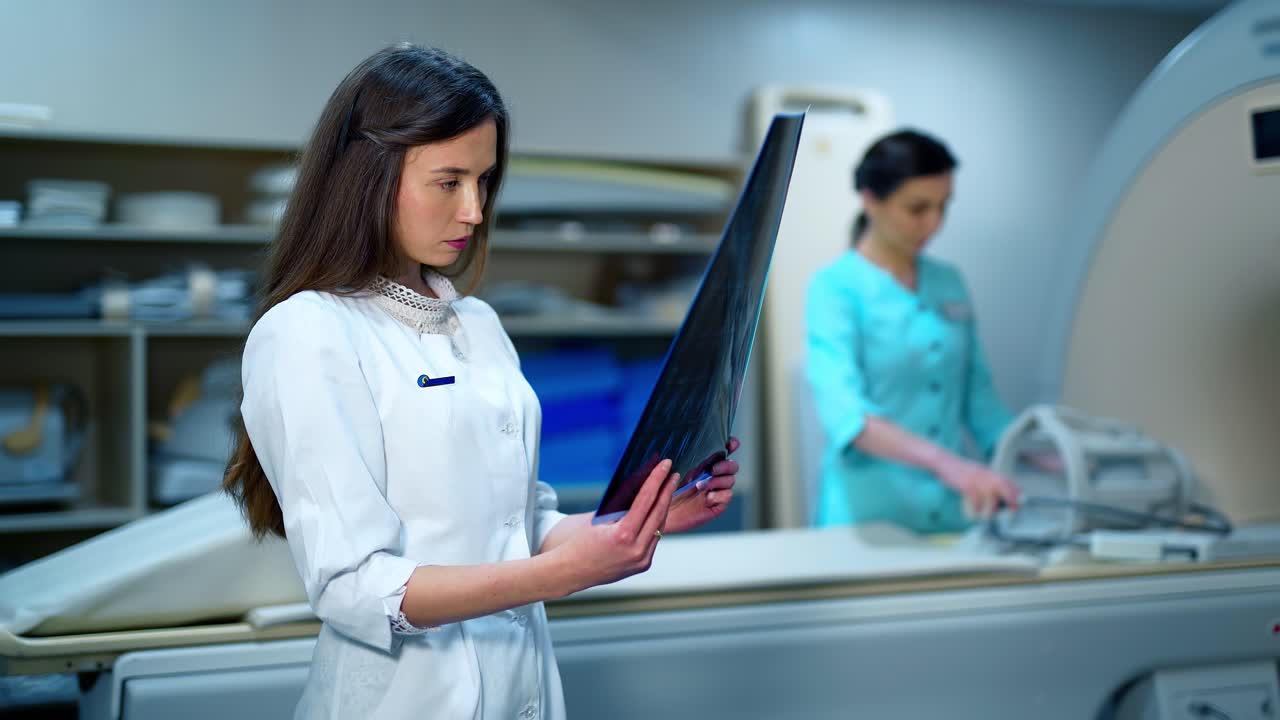 Young medical doctor with an x-ray. Beautiful female expert examining radiograph picture of a patient in the modern medical room in clinic.