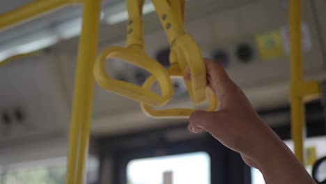 a hand gripping a yellow handle inside a bus