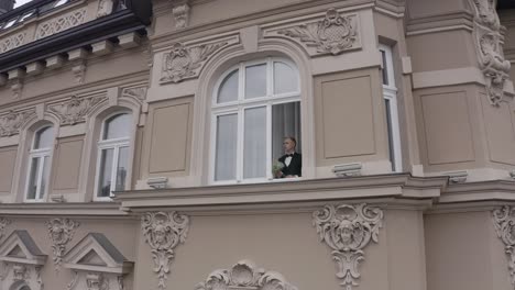 groom in suit looking out window of a building