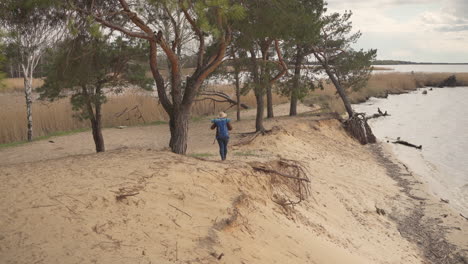 숲의 나무와 아름다운 호수 옆을 걷고 있는 인식할 수 없는 모험적인 빨간 머리 여성 1