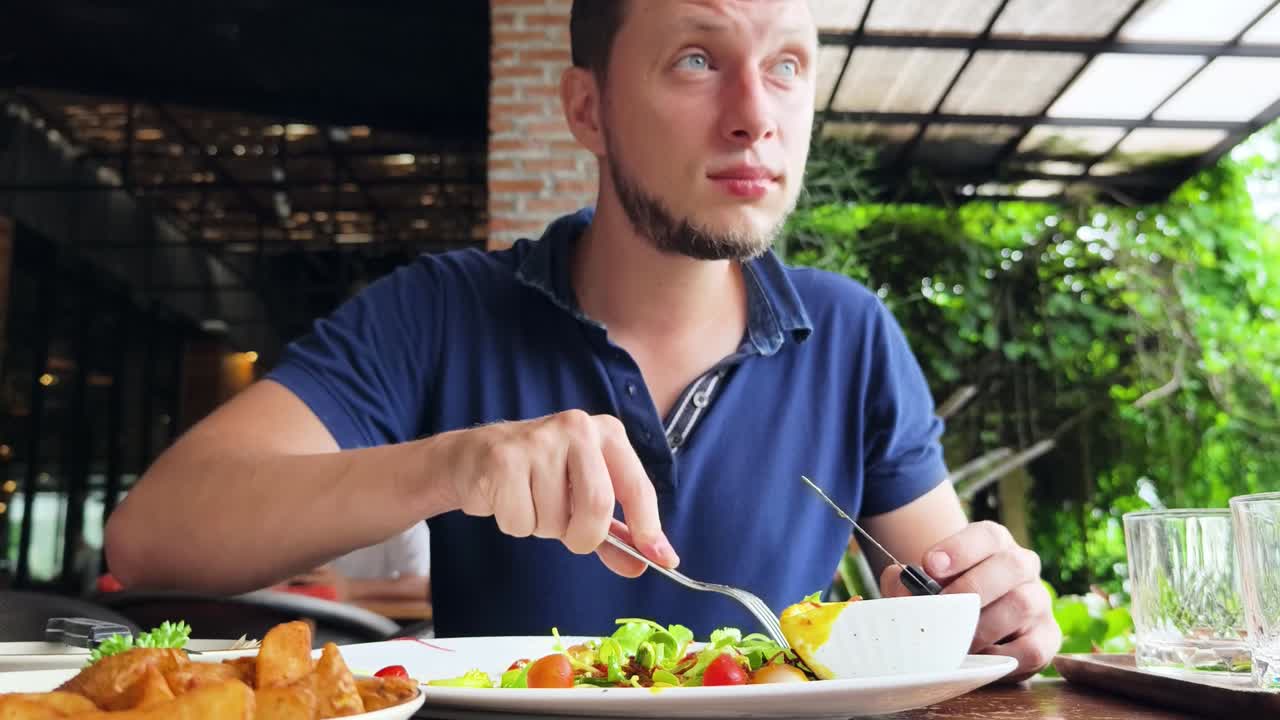 hombre comiendo ensalada y papas fritas en un restaurante