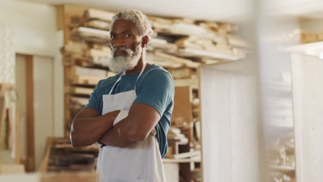 retrato de un carpintero afroamericano con un delantal de pie en una tienda de carpintería