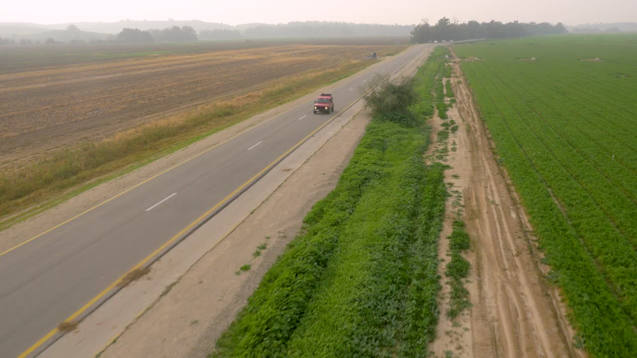 Drone tracking red SUV vehicle driving on quiet country road
