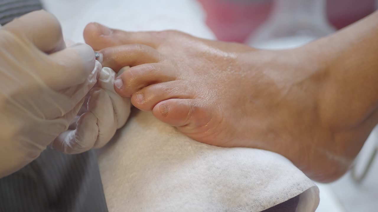 Close-up of Nail Technician Performing Pedicure on Woman's Foot