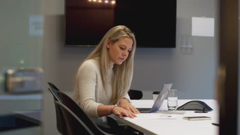 stressed businesswoman working late in office meeting room using laptop