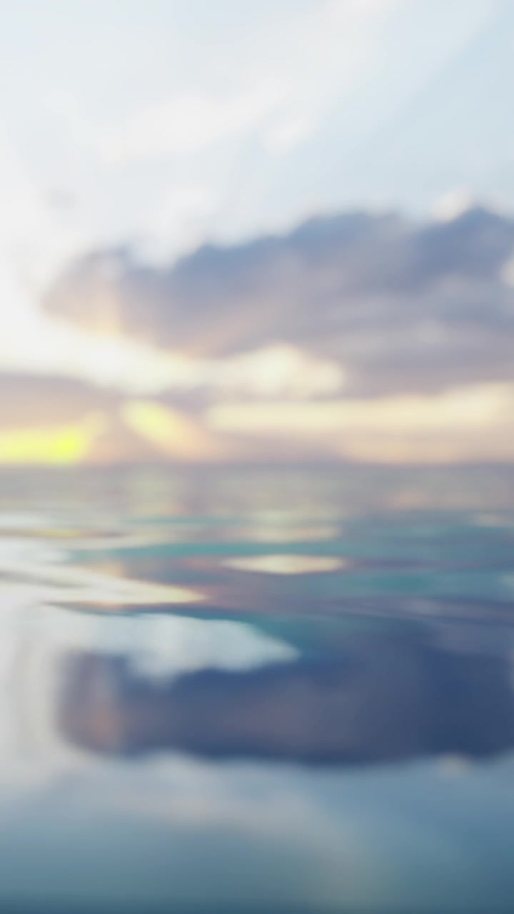 Sunset over calm water with clouds reflecting on the surface