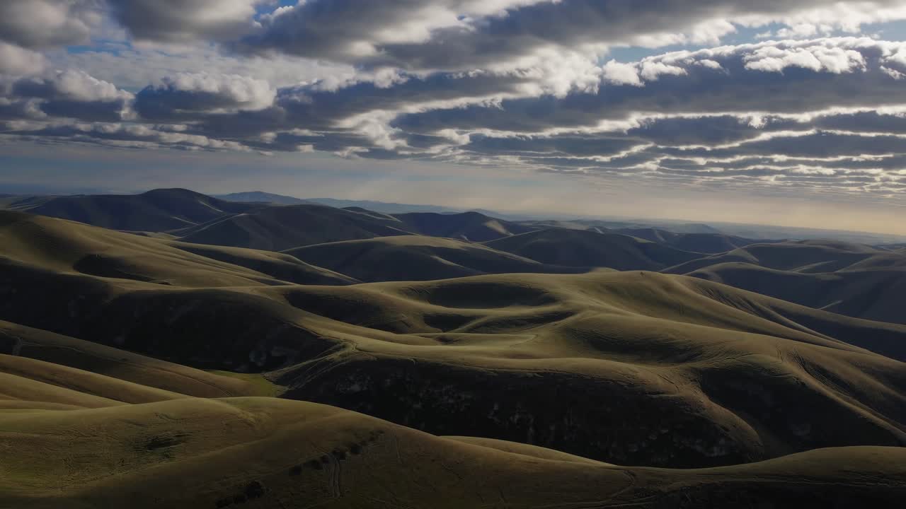 Aerial video captures rolling hills under dramatic, layered clouds