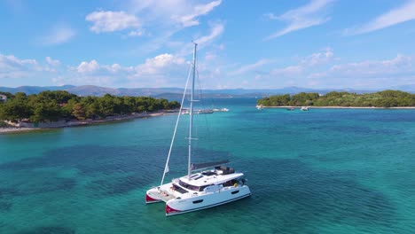 flight on the bay in which yachts drift surrounded by green trees against the backdrop of mountains and a mountain road under blue sky with clouds