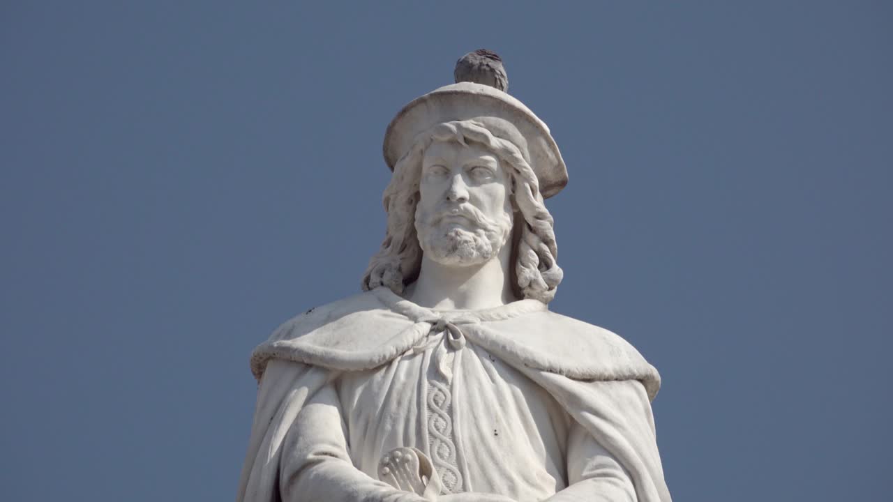 A dove sits on the head of the Walther von der Vogelweide statue on a sunny day
