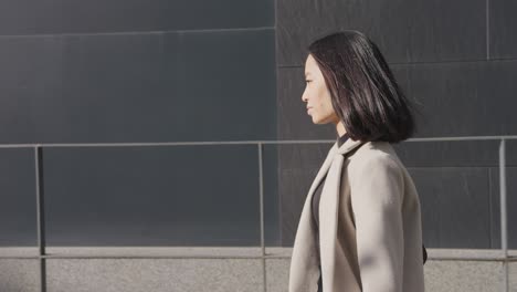 side view of an asian businesswoman walking in the downtown