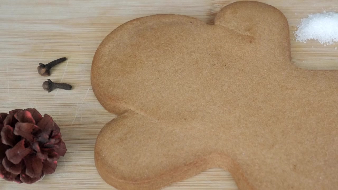 Suuri piparkakku puulaudalla mausteiden ja leivonta-ainesten kera.