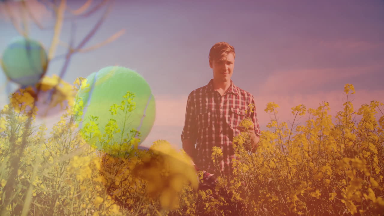 Man holding flower in rural field, displaying surreal tennis ball overlay for marketing design