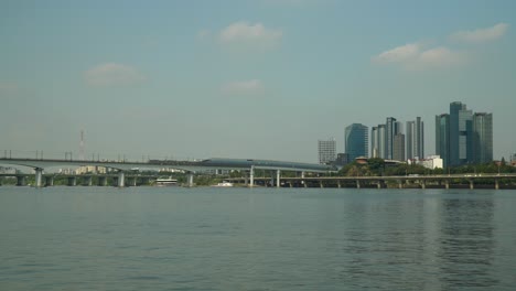 two subway railway trains moving in different directions on dangsan railroad bridge over han river, traffic on gangbyeonbuk-ro expressway, seah tower, kb insurance towers, mecenatpolis, seoul hapjeong