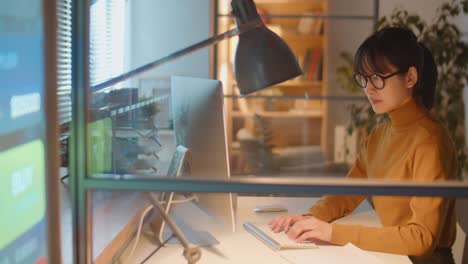 asian businesswoman working on computer in office at night