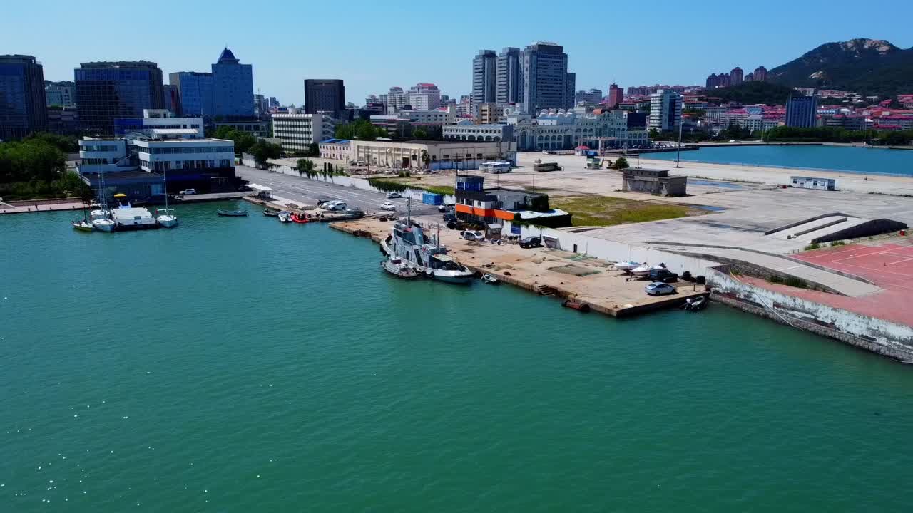 Aerial orbit view of wharf or pier with docked boats and beautiful skyline in Weihai - China