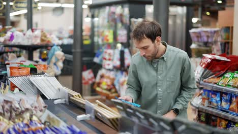 man walks through the supermarket and takes chocolate from the shelf. reading labels and ingredients