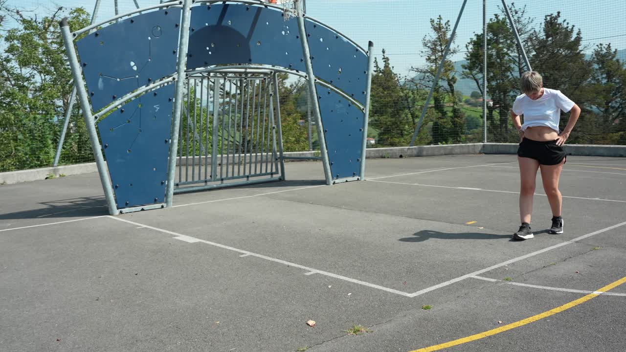 屋外のスポーツコートでボール遊びをする女性と少年