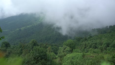 day timelapse of fog movement over a hill with the sun rays shining in the background