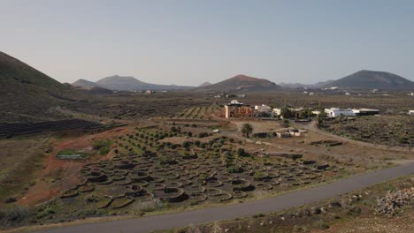 Un-Coche-Circulando-Por-Edificios-Poblados-Con-Un-Jardín-En-La-Isla-De-Lanzarote,-España