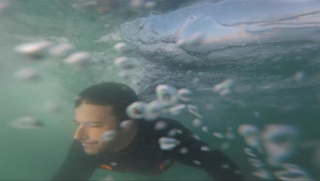 Hombre-Surfista-Se-Sumerge-Con-Tabla-De-Surf-Bajo-El-Agua-Para-Pasar-La-Ola-Del-Océano