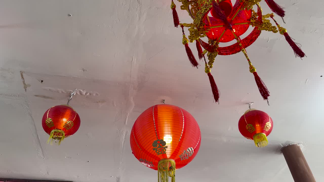 Red Chinese lanterns hang from a white ceiling, camera tilts upward, soft indoor lighting